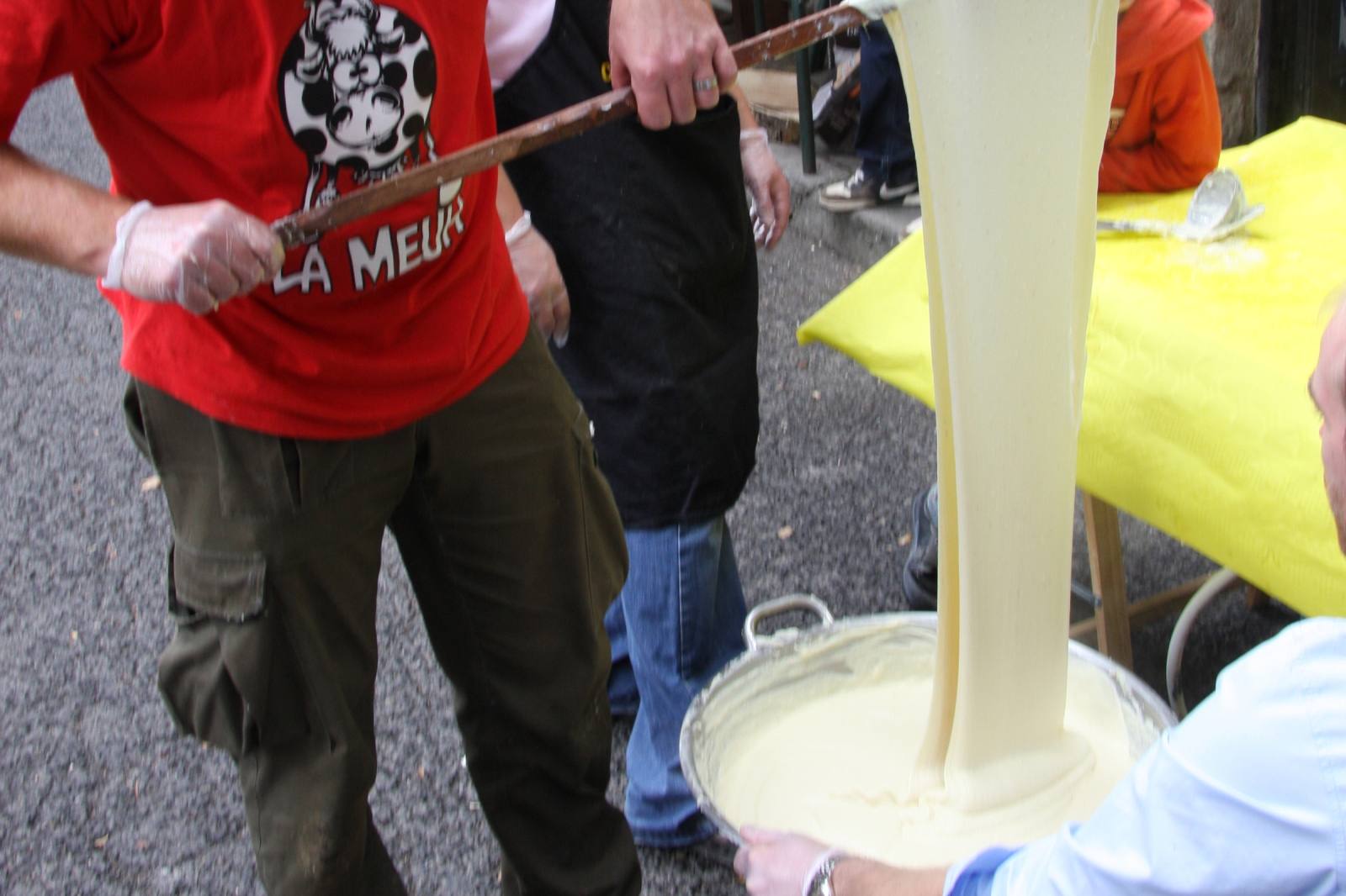 Aligot filé à la louche depuis un grand chaudron, texture élastique caractéristique de la tome fraîche fondue